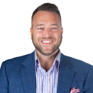 Todd Roberts smiling in a blue plaid blazer and striped shirt against a white background.